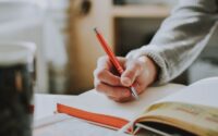 person holding orange pen